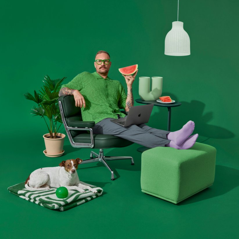 Een man zit op een stoel, met een hond naast zich.