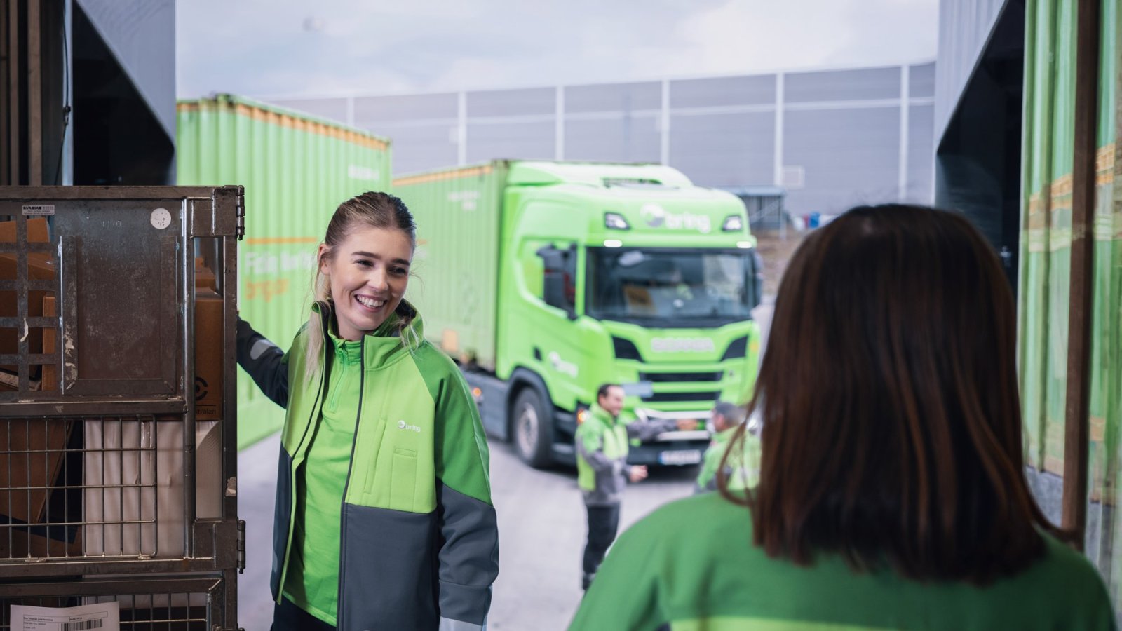 Woman holding a parcel container in front of a truck